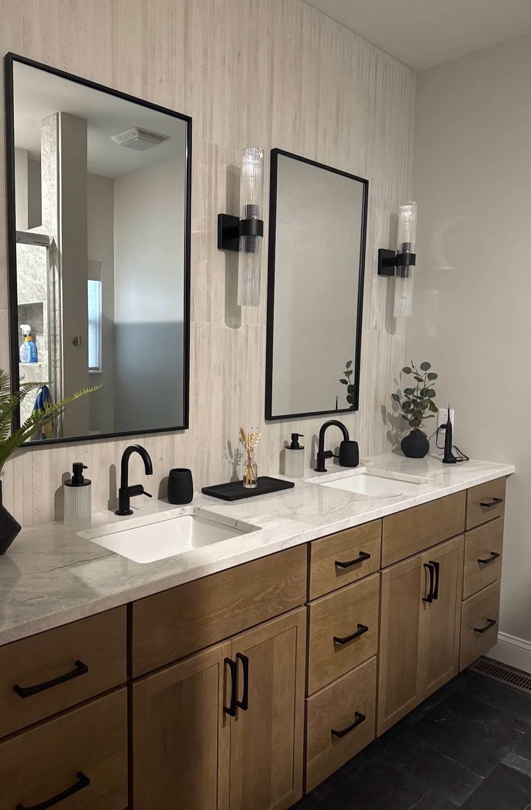 Double vanity with wood cabinets, marble-look countertop and black fixtures
