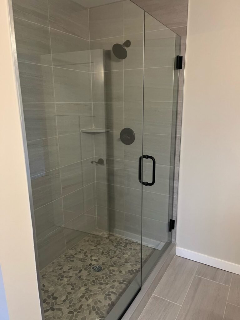 Frameless glass walk-in shower with black hardware and pebble floor, Middletown Bath Co., Orange County, NY
